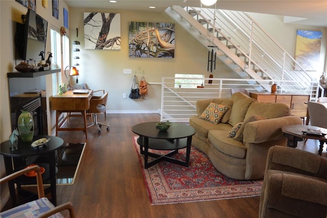 living area with baseboards, wood finished floors, and a tile fireplace