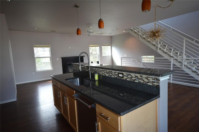 kitchen with a sink, dark wood-style floors, dishwasher, tasteful backsplash, and a center island with sink