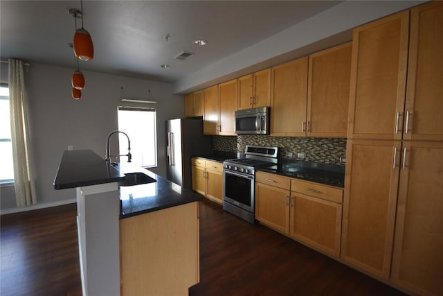 kitchen featuring visible vents, dark countertops, appliances with stainless steel finishes, a sink, and backsplash