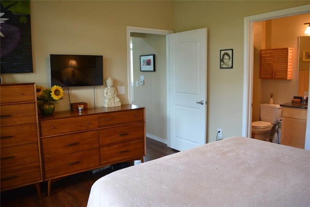 bedroom with dark wood-style floors, ensuite bath, and baseboards