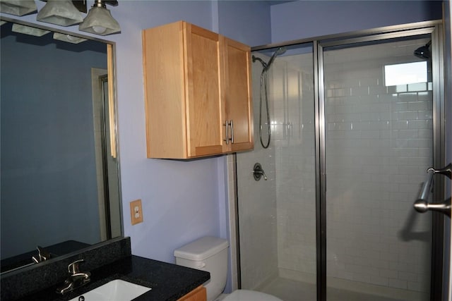 bathroom with vanity, a shower stall, and toilet