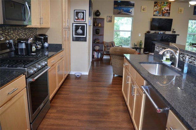 kitchen featuring dark wood-style flooring, backsplash, appliances with stainless steel finishes, open floor plan, and a sink