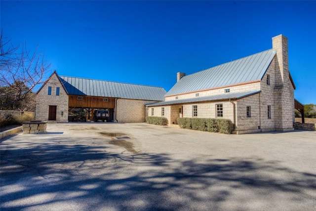 exterior space with a standing seam roof, metal roof, and a chimney