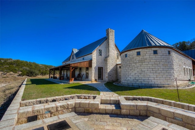 back of property featuring a patio area, a yard, metal roof, and a standing seam roof