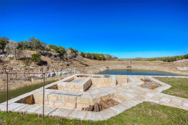 view of swimming pool featuring a water view and a fire pit