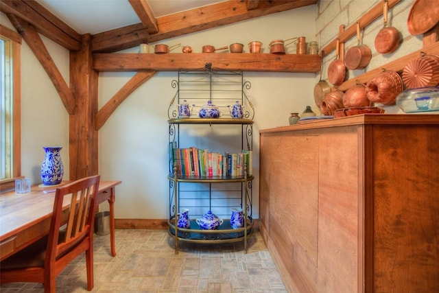 interior space with baseboards, stone finish floor, and beamed ceiling