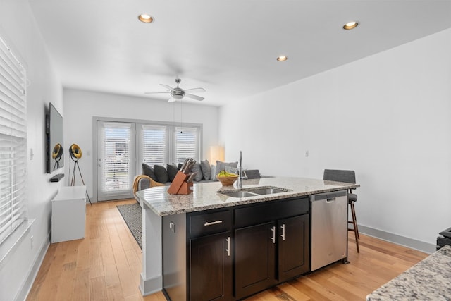 kitchen with a sink, light wood-style flooring, a center island with sink, and stainless steel dishwasher