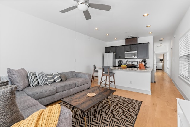 living area featuring a ceiling fan, recessed lighting, and light wood finished floors