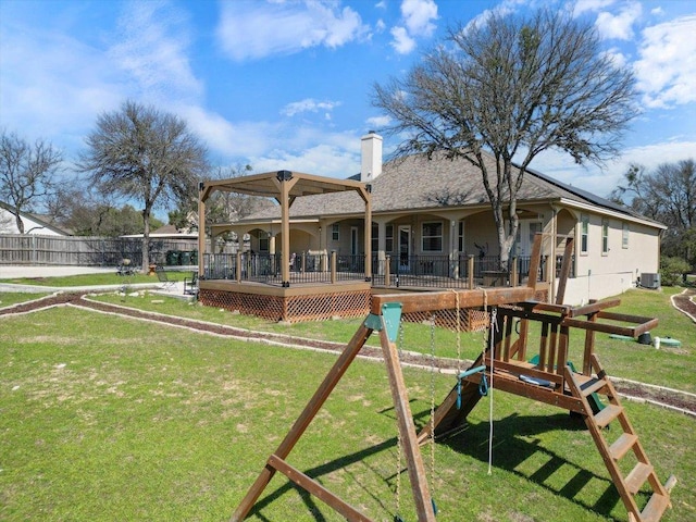 rear view of house with playground community, a lawn, a chimney, and fence