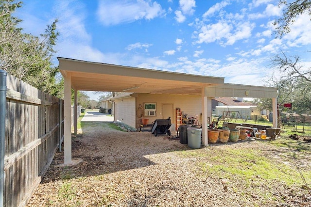 view of parking / parking lot featuring fence and a carport