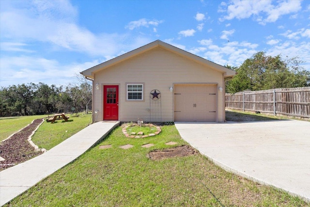 view of front facade featuring concrete driveway, fence, and a front lawn