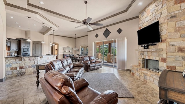 living room with a high ceiling, a fireplace, a ceiling fan, and crown molding