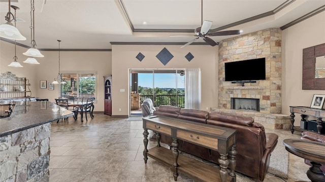 living area with a fireplace, a tray ceiling, and ornamental molding