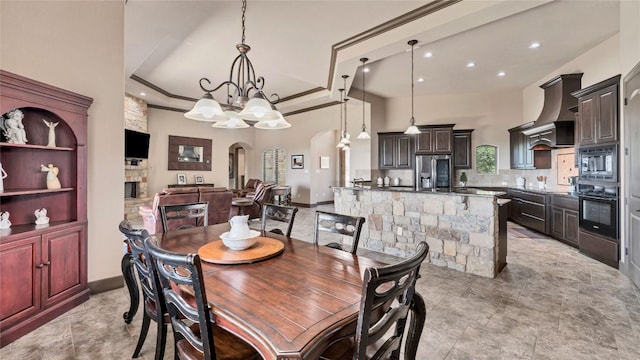 dining room featuring arched walkways, a notable chandelier, a fireplace, ornamental molding, and a tray ceiling