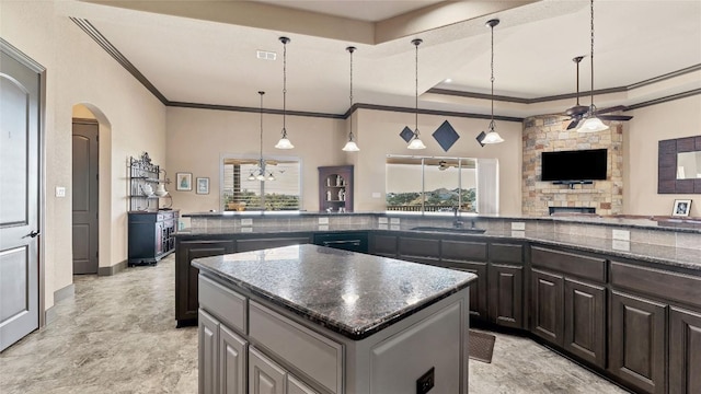 kitchen with a kitchen island, a sink, visible vents, a tray ceiling, and crown molding