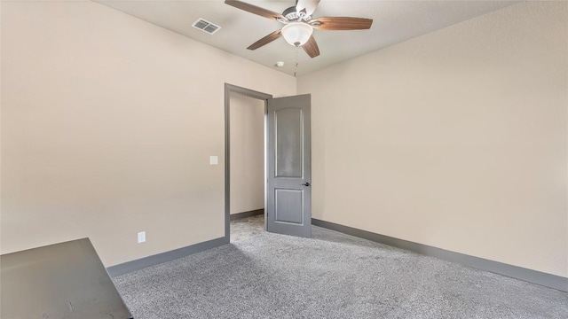 carpeted empty room featuring ceiling fan, visible vents, and baseboards