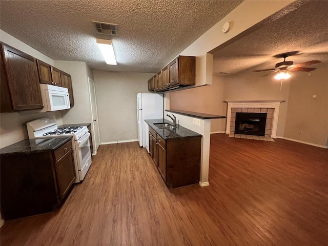 kitchen featuring white appliances, visible vents, open floor plan, wood finished floors, and a sink