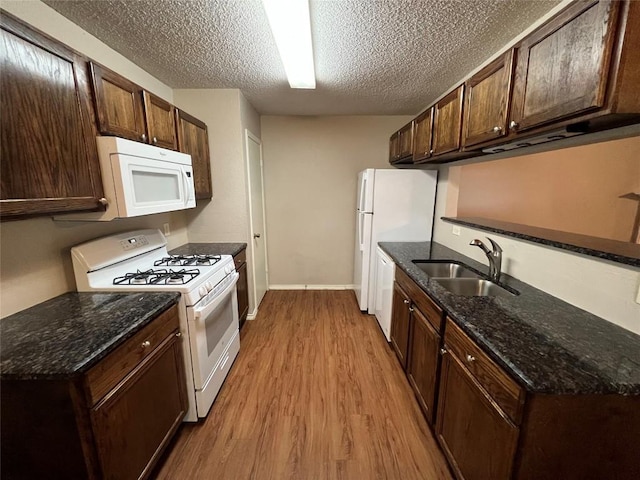 kitchen featuring dark brown cabinetry, white appliances, light wood finished floors, a textured ceiling, and a sink