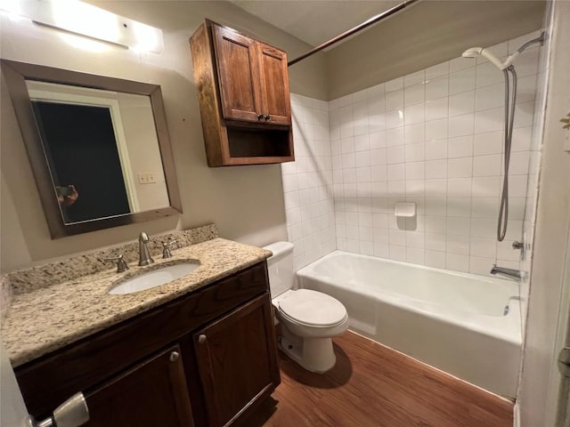 bathroom featuring toilet,  shower combination, wood finished floors, and vanity