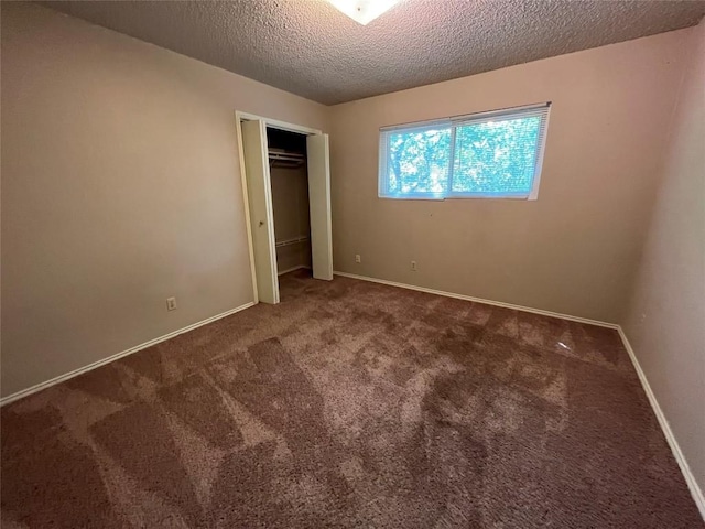 unfurnished bedroom featuring carpet floors, a closet, a textured ceiling, and baseboards