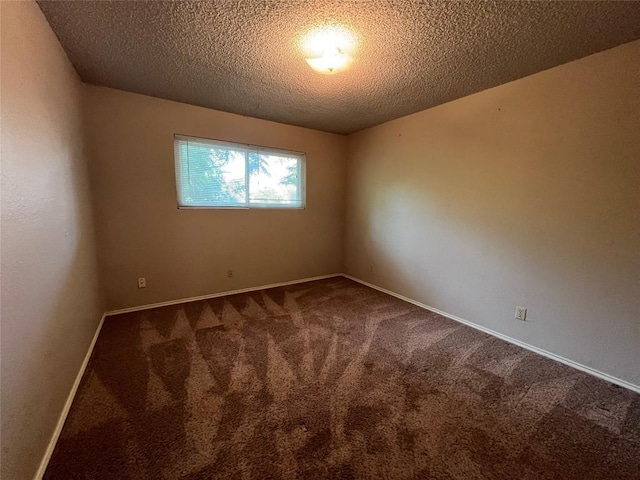 spare room with carpet, baseboards, and a textured ceiling