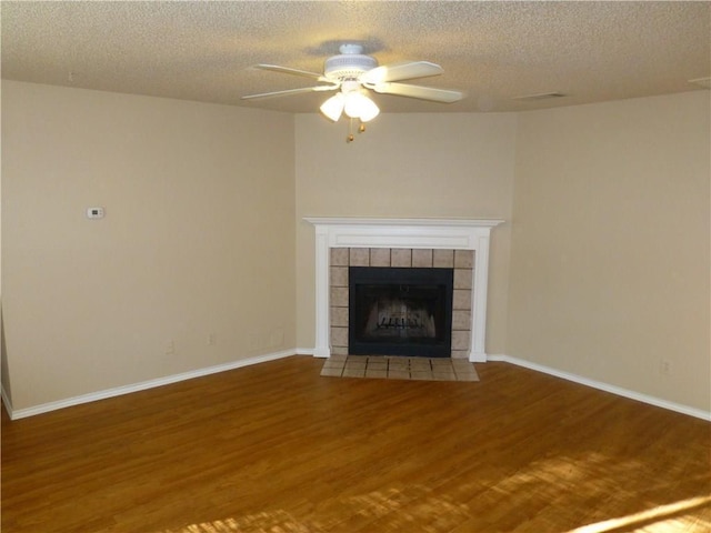 unfurnished living room with baseboards, a tiled fireplace, and wood finished floors