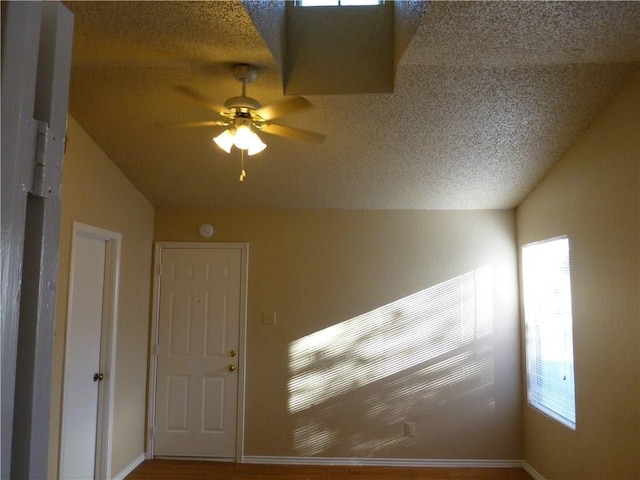 additional living space with ceiling fan, vaulted ceiling, and a textured ceiling