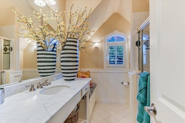 full bath with a shower with door, lofted ceiling, wainscoting, vanity, and tile patterned floors