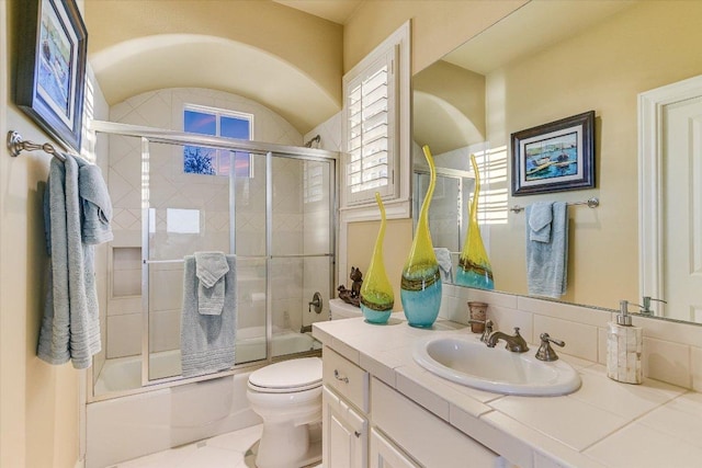 full bath with enclosed tub / shower combo, vanity, and toilet