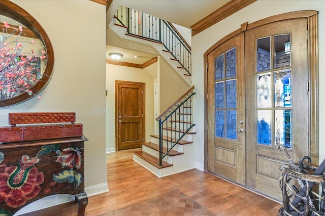 foyer featuring french doors, crown molding, stairway, wood finished floors, and baseboards