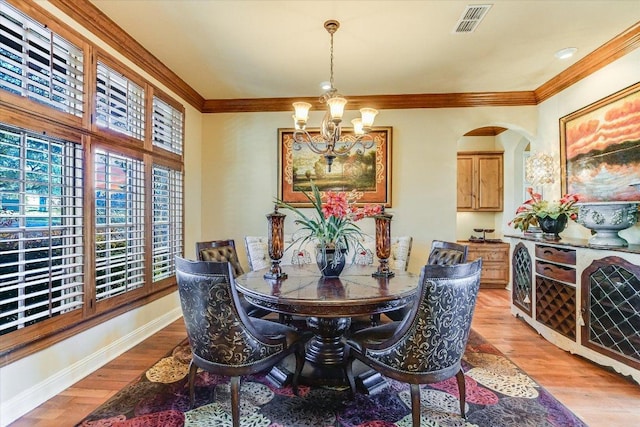 dining space with a notable chandelier, ornamental molding, baseboards, and light wood-style floors