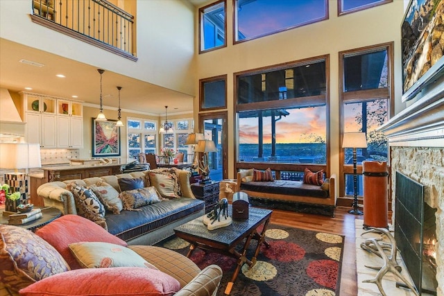 living room featuring a fireplace, wood finished floors, and a towering ceiling