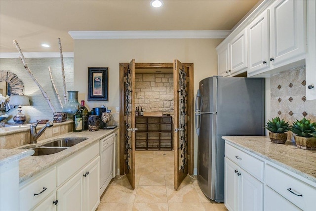 kitchen featuring crown molding, freestanding refrigerator, white cabinetry, white dishwasher, and a sink