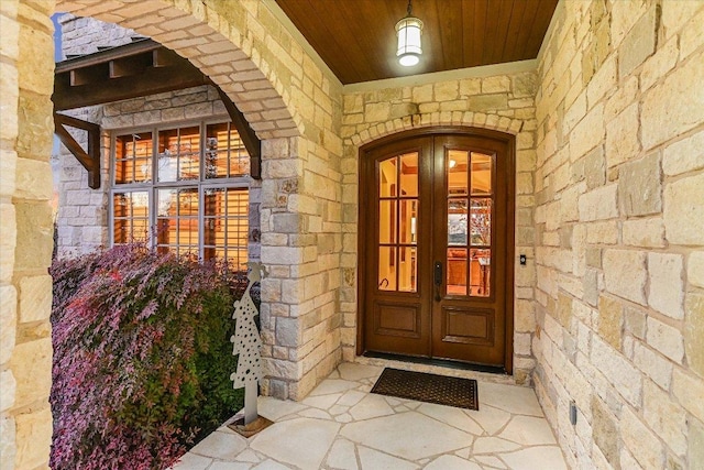 property entrance with stone siding and french doors