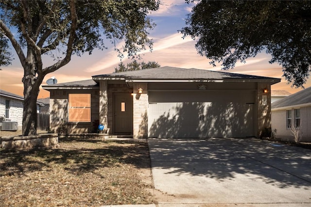 view of front of house featuring a garage, cooling unit, concrete driveway, and brick siding