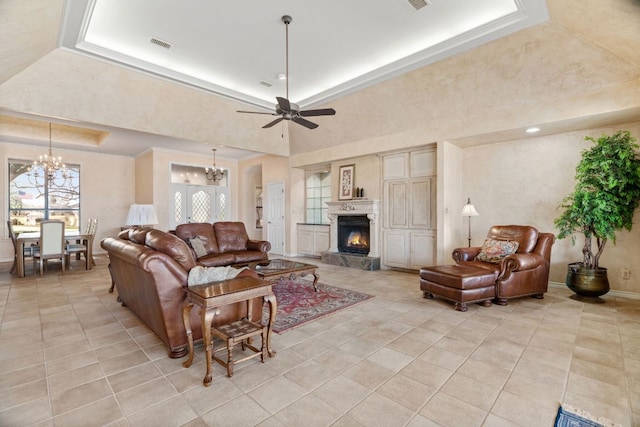 1306 Far W Rd, Horseshoe Bay, TX 78657 - living room featuring a chandelier, a tray ceiling, light tile patterned flooring, a warm lit fireplace, and ceiling fan