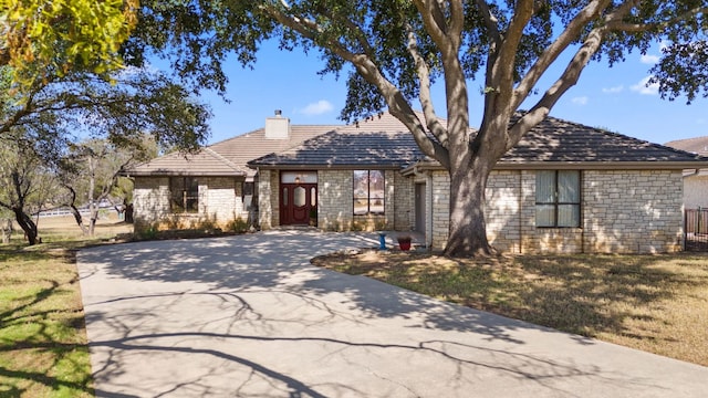 1306 Far W Rd, Horseshoe Bay, TX 78657 - view of front of property featuring concrete driveway, a chimney, stone siding, and a front lawn