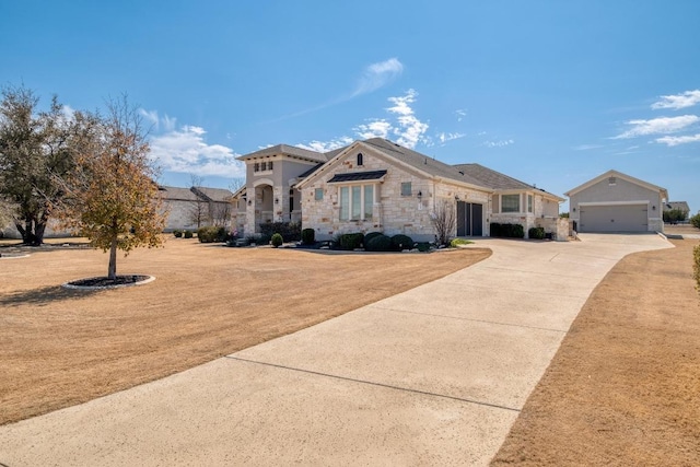 view of front of property with an outbuilding, stone siding, driveway, and an attached garage