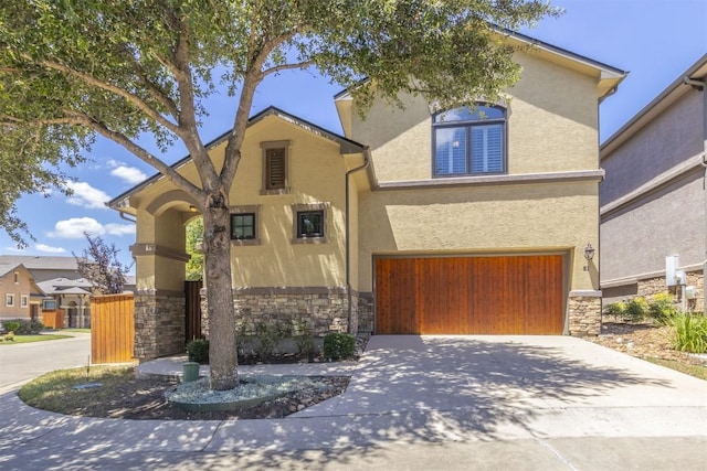 view of front facade with stone siding, driveway, an attached garage, and stucco siding