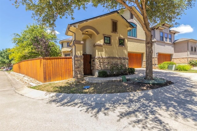 view of front of property featuring stone siding, fence, concrete driveway, and stucco siding