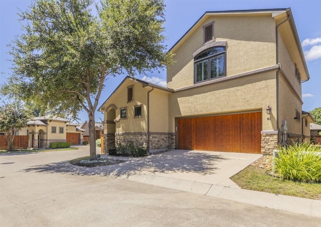 view of front facade with a garage, stone siding, driveway, and stucco siding