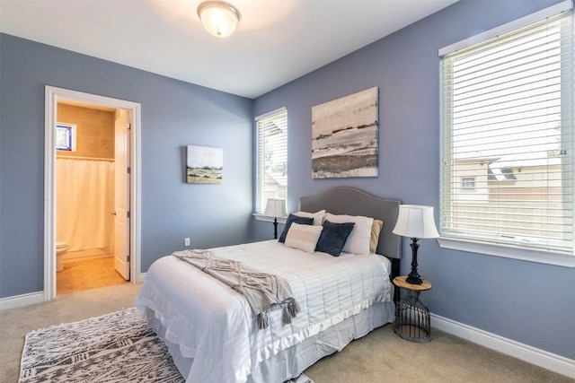 bedroom with light carpet, ensuite bathroom, and baseboards