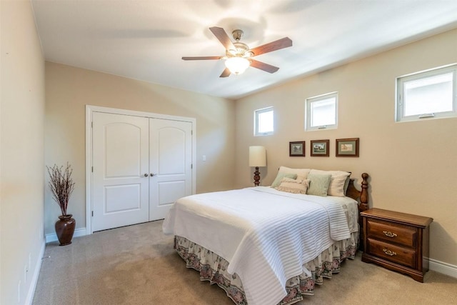 bedroom with ceiling fan, baseboards, a closet, and light colored carpet