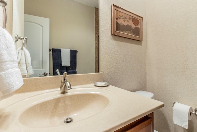 bathroom featuring a textured wall and vanity