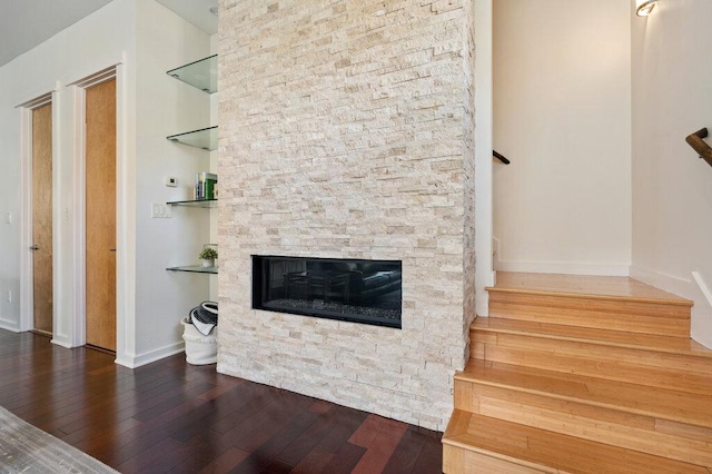 living room with stairs, a fireplace, hardwood / wood-style flooring, and baseboards