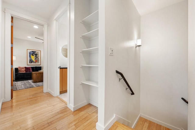 interior space with light wood-type flooring, baseboards, an upstairs landing, and recessed lighting