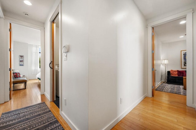 hall featuring light wood-style flooring and baseboards