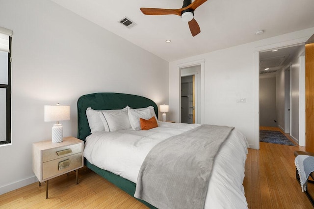 bedroom with ceiling fan, wood finished floors, visible vents, and baseboards