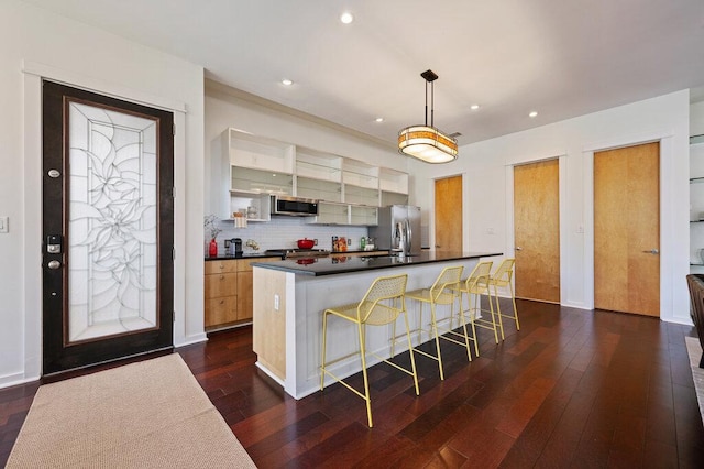 kitchen with appliances with stainless steel finishes, dark countertops, dark wood finished floors, and tasteful backsplash