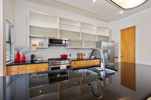 kitchen with open shelves, dark countertops, backsplash, appliances with stainless steel finishes, and a sink